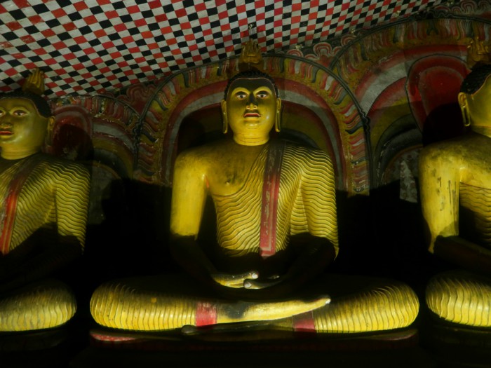 a yellow Buddha statue in the cave temple of Dambulla in Sri Lanka 