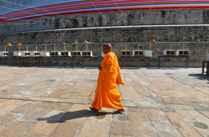 A Buddhist monk in an orange gown walking around the Ruwanvelisaya stupa in Anuradhapura in Sri Lanka 