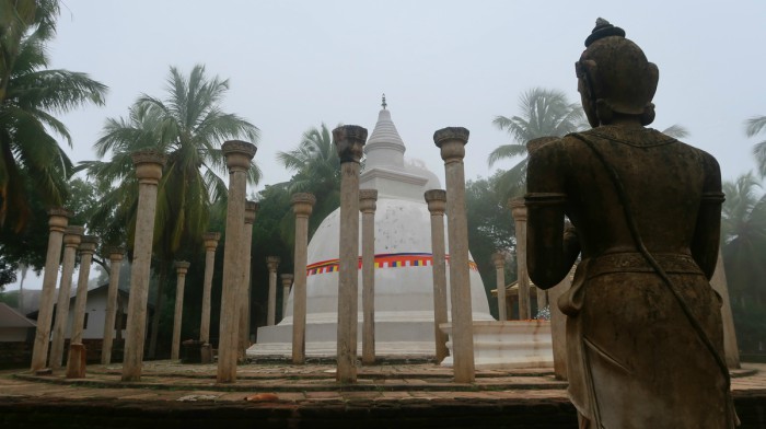 temples and sacred sites of sri lanka - mihintale stupa surrounded by old pillars and a buddha statute in sri lanka 