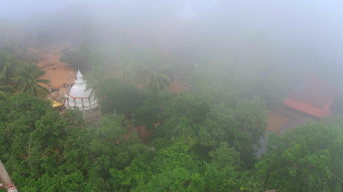 Mihintale stupa as seen from above and surrounded by the fog and green palm trees