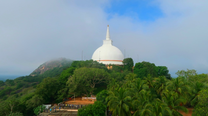a big white maha stupa surrounded by tropical green palm trees in mihintale sri lanka 