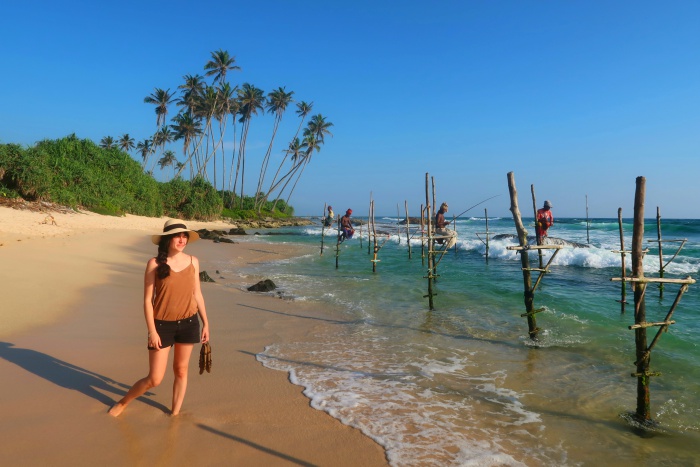 traditional fishermen of sri lanka and a girl standing on the sandy beach with her feet in the sand 