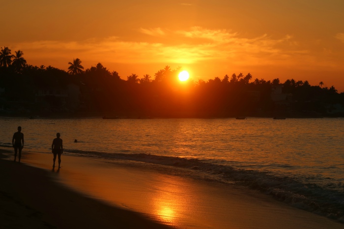 orange sunrise and people walking on the beach in unawatuna sri lanka 
