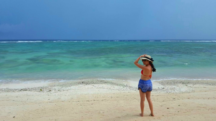 a girl on a sandy beach, blue turquoise sea and stormy sky in gili trawangan indonesia
