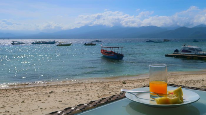 breakfast on the beach with boats and islands in the background in gili trawangan indonesia