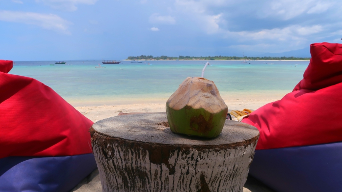 coconut with a straw on a sandy beach in gili trawangan indonesia