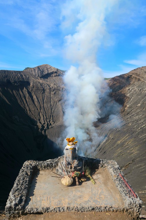 smoke coming out of a bromo volcano crater and a hindu shrine with the god ganesha statue in java indonesia 