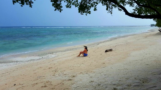 a girl sitting on a sandy beach in gili trawangan indonesia