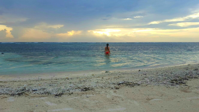 a girl watching the sunset in the middle of the sea and a sandy beach in gili trawangan indonesia