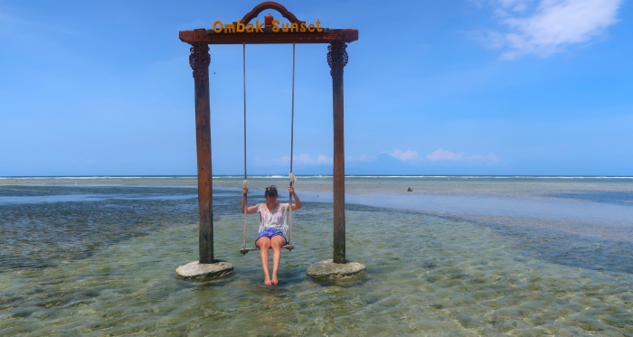 a girl on a swing in the middle of the sea in gili trawangan indonesia