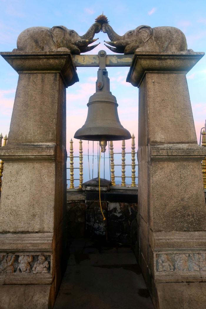 the wish bell and two stone elephants above it at the top of sri pada adams peak in sri lanka